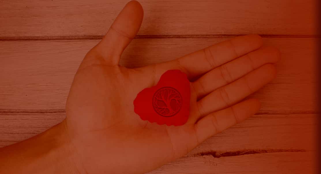 Hand holding a heart with a Grove Bay Hospitality emblem