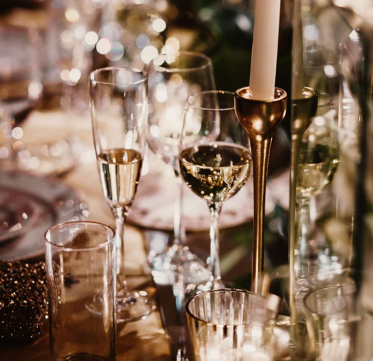 Elegant event table set with champagne glasses, candles, and white floral arrangements.
