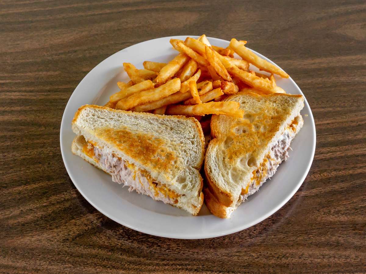 Toasted tuna melt sandwich and crispy golden french fries served on a white plate at Miller's Cafe.