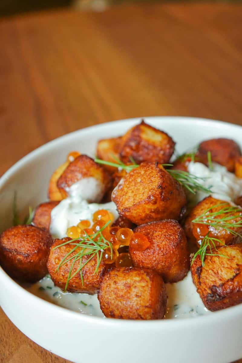Golden-brown potato dumplings, crispy on the outside and tender on the inside, served with a savory sauce and garnished with herbs.