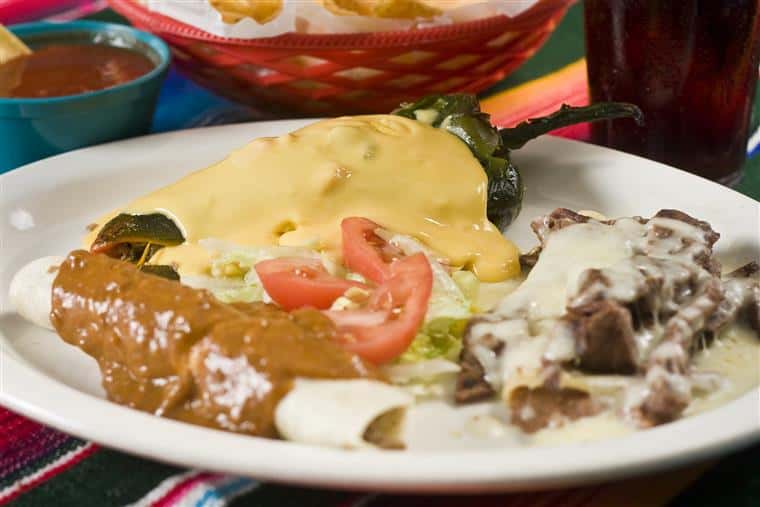 Combination of Mexican dishes served in a plate topped with sauces and served with garnish