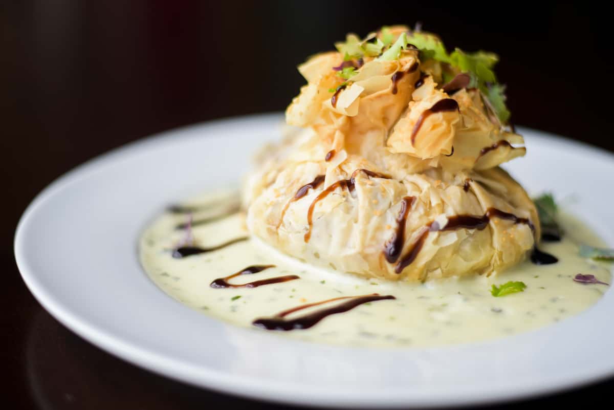Crisp phyllo dough wrapped around seasoned veggies & mozzarella, baked until golden, & served with basil cream.