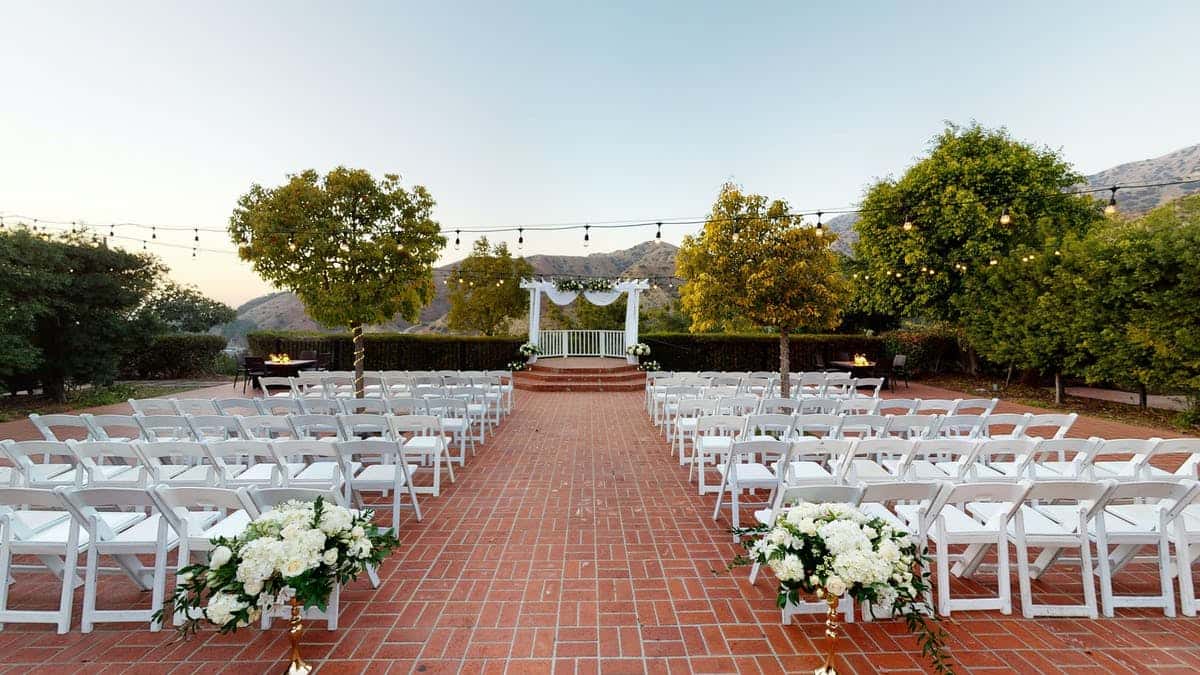 Courtyard set up for a wedding with an arch with white rose decor
