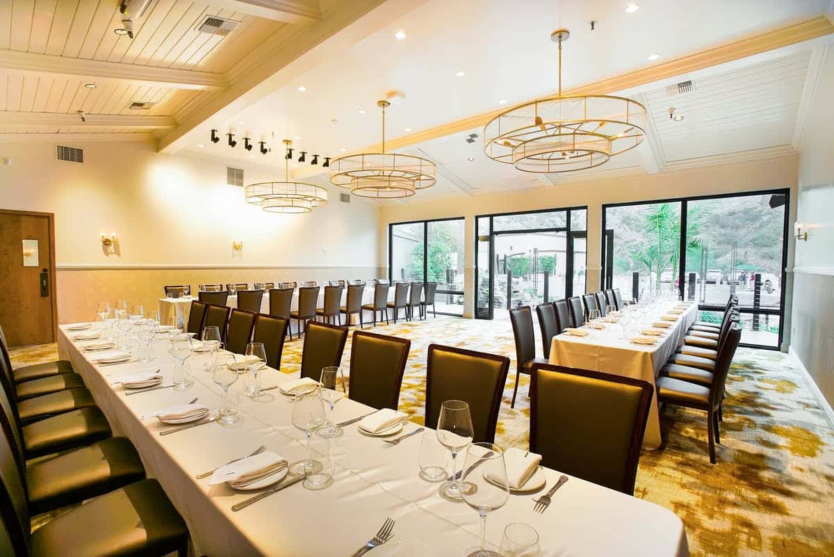 Waterfront event space set up with white table scape, wine glasses and black chairs for a corporate event