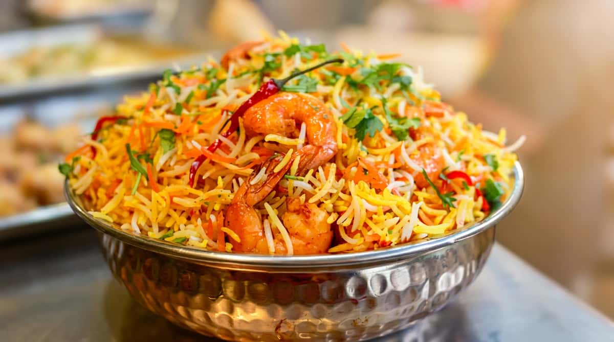 A bowl of shrimp biryani with fragrant basmati rice, herbs, and aromatic Indian spices.