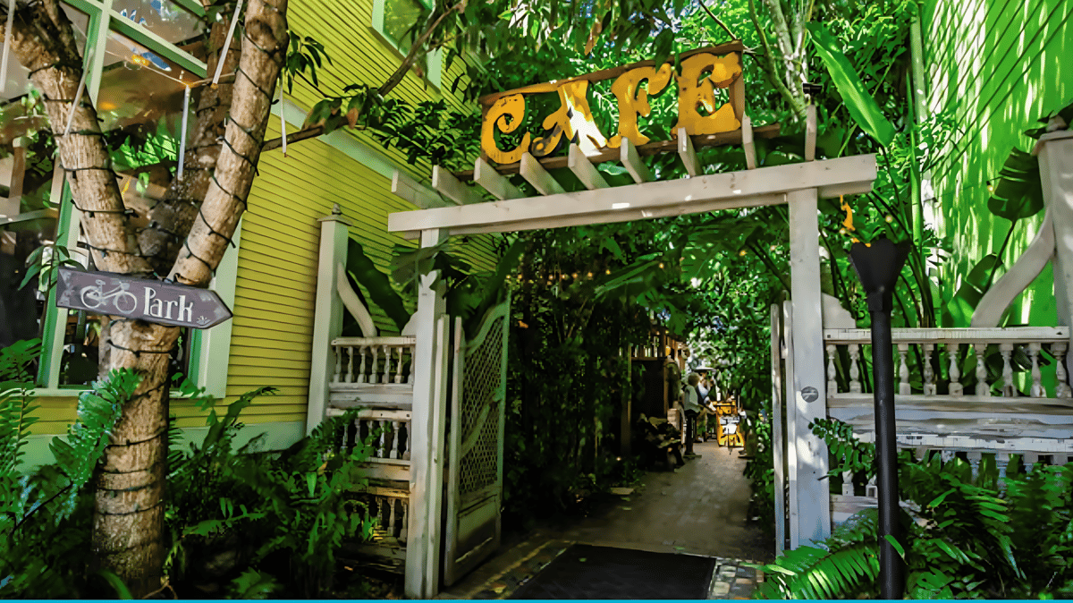 Lush greenery surrounding the café entrance, inviting guests into our hidden garden dining space.