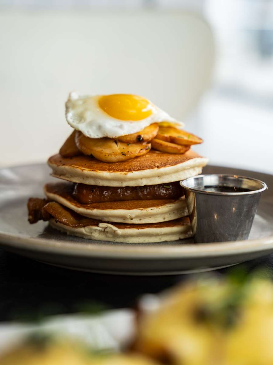 A stack of pancakes topped with a sunny side up egg