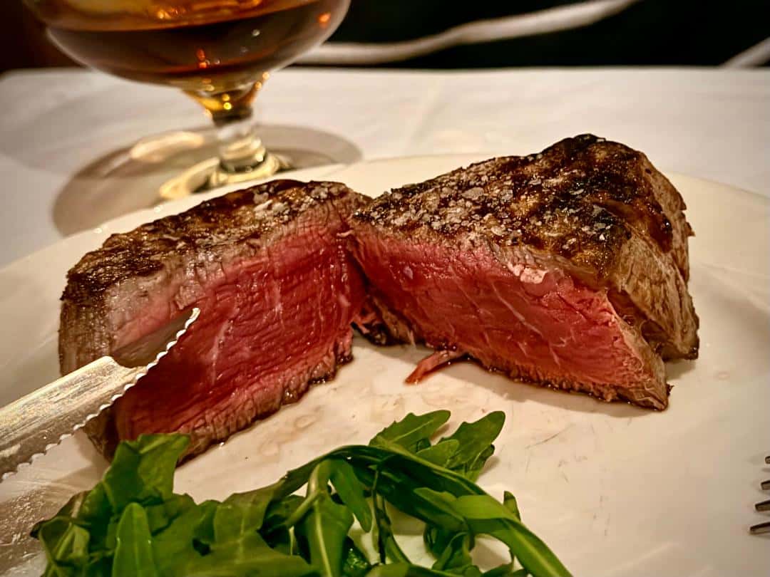 rare filet cut half on white plate with leafy greens