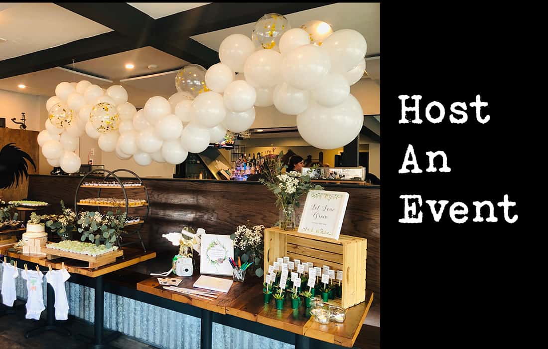 Host an event Baby shower with big white balloon arch hanging from ceiling.