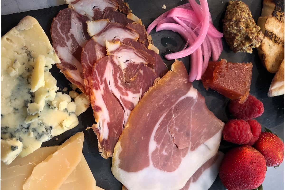 Charcuterie board with meat, cheese and raspberries
