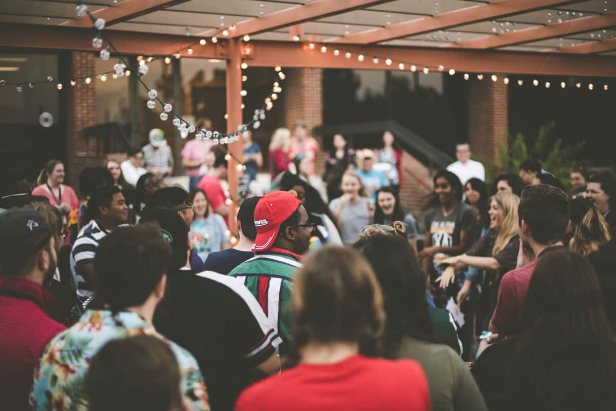 Crowd at an outdoor party with string lights