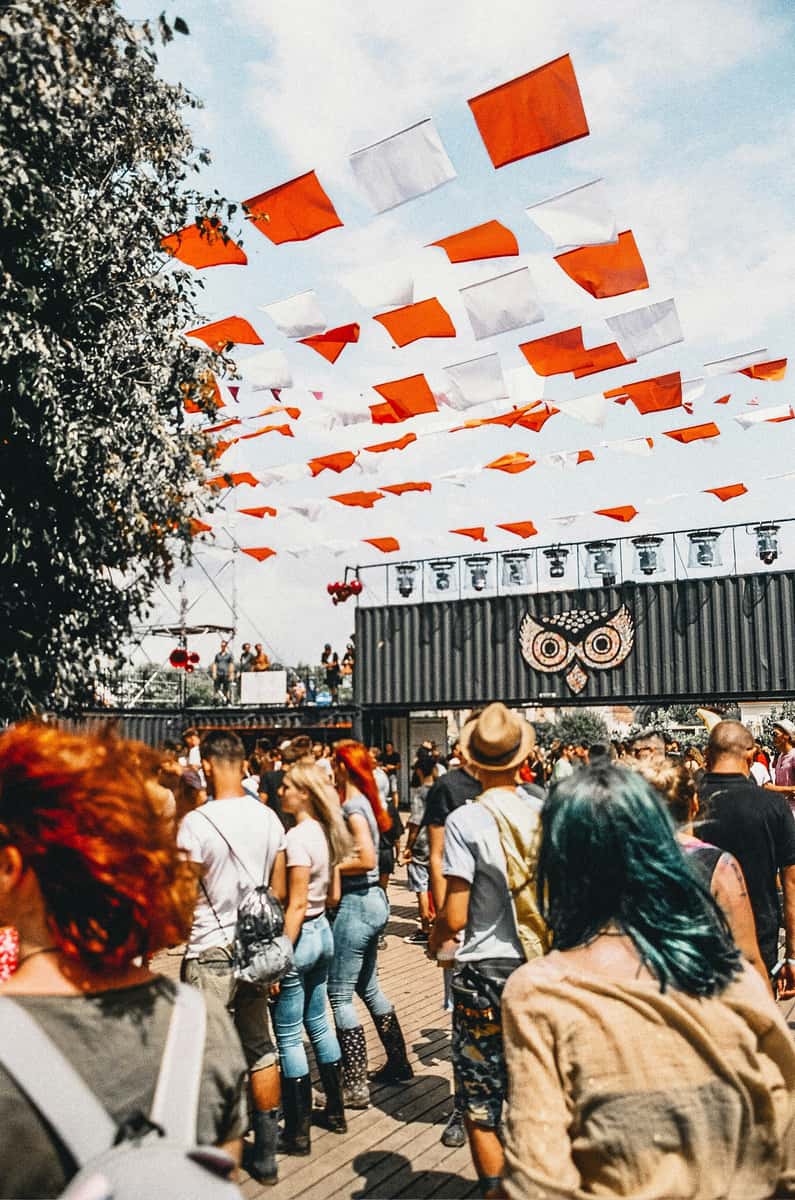 People walking at a music festival under red and white flags