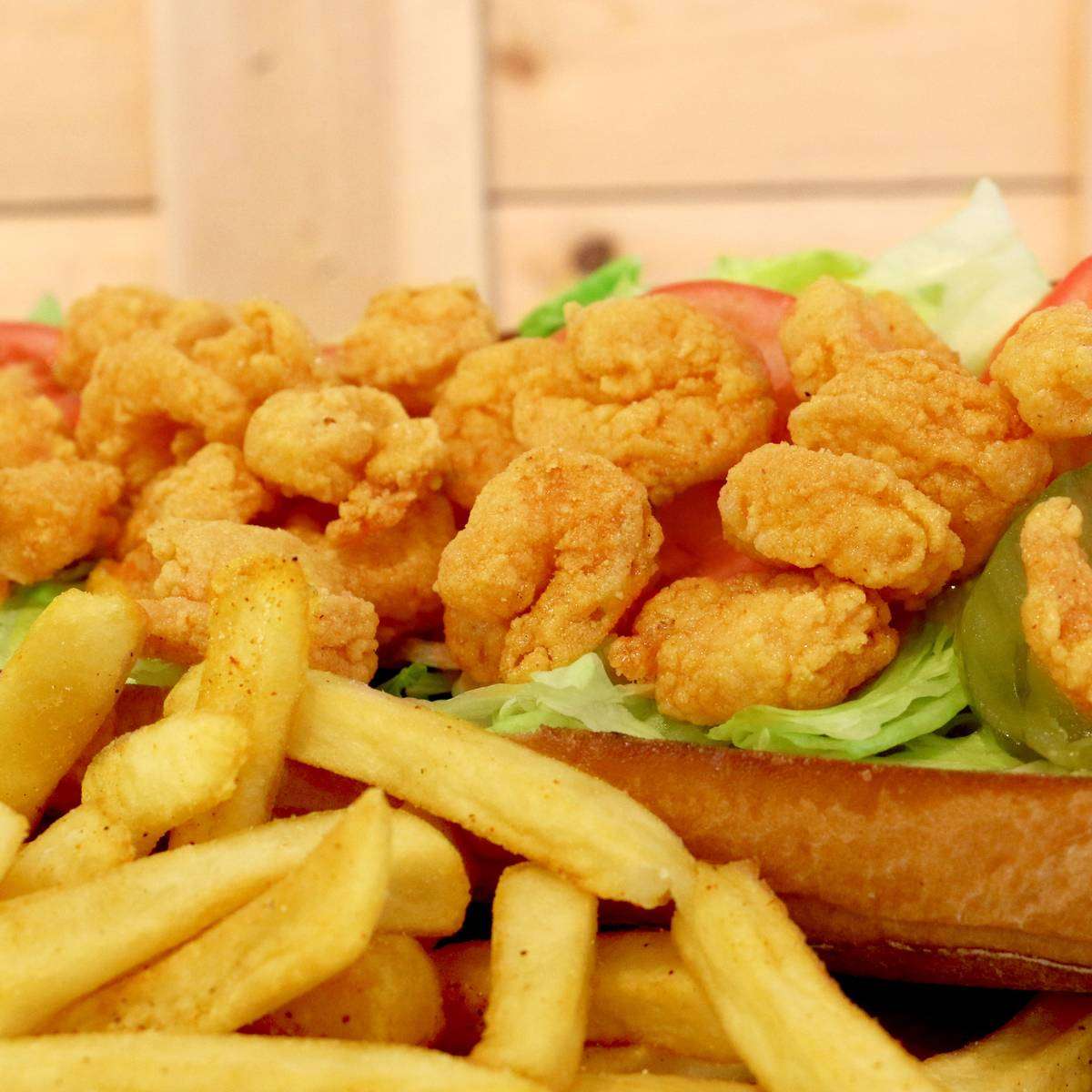 Fried shrimp po'boy sandwich with lettuce, served with french fries