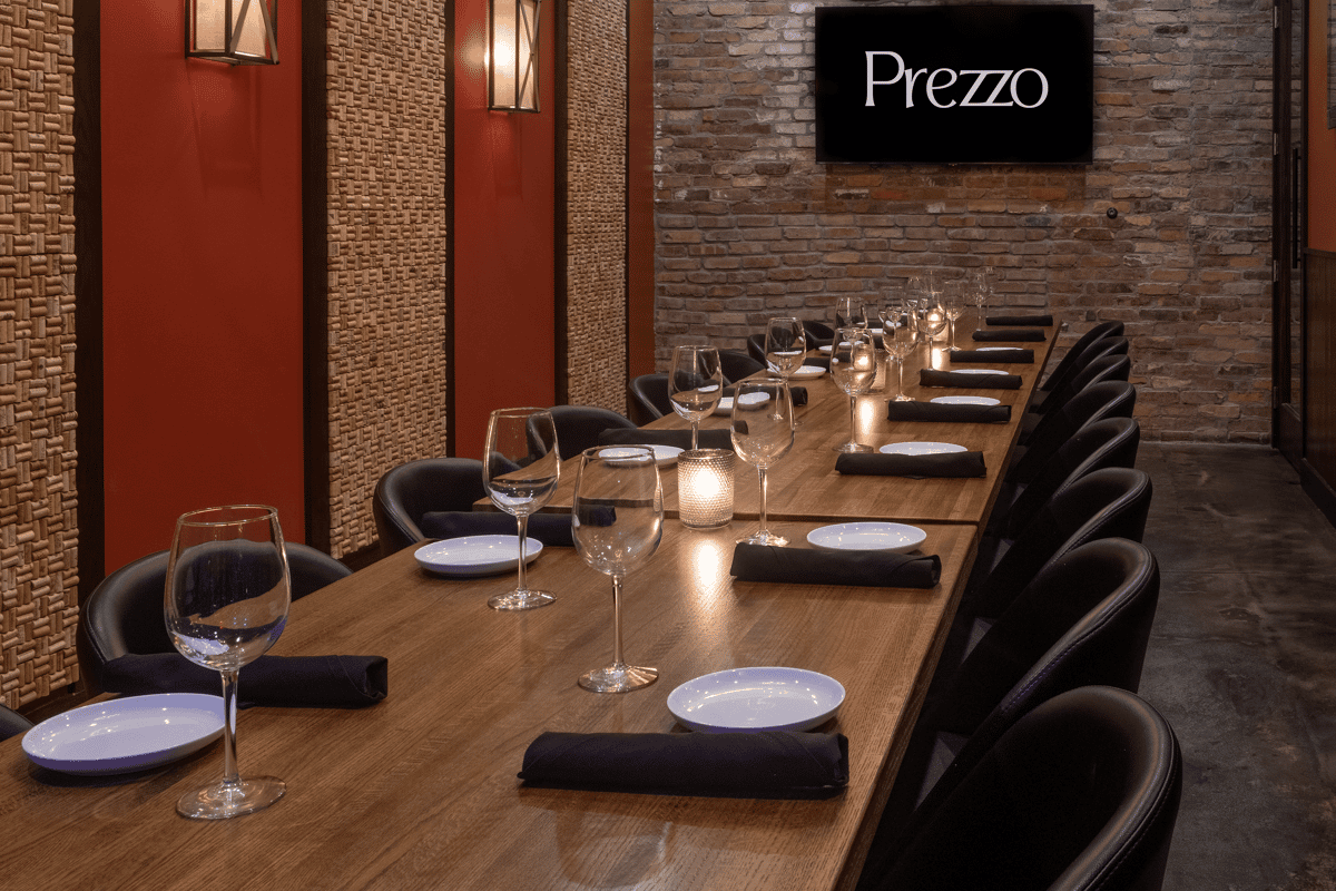 Elegant private dining room at Prezzo, set with wine glasses, candles, and black napkins on a long wooden table.