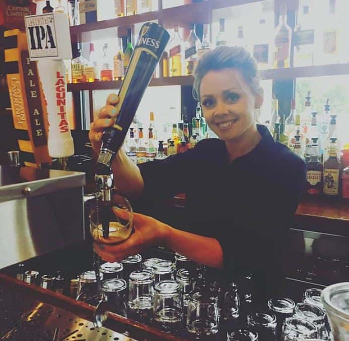 Bartender smiling pouring a beer from a beer tap