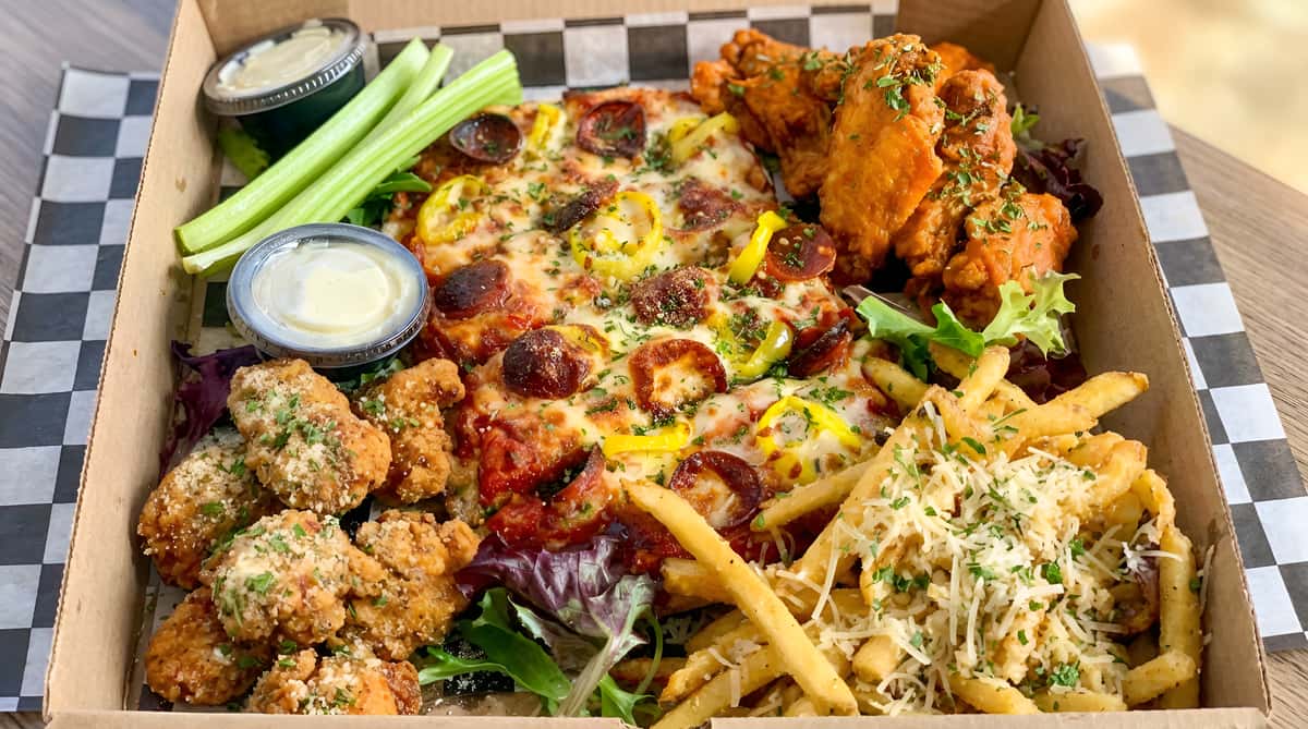 Pizza with pepperoni and yellow peppers, fried chicken wings, french fries with cheese, celery, and dipping sauces.