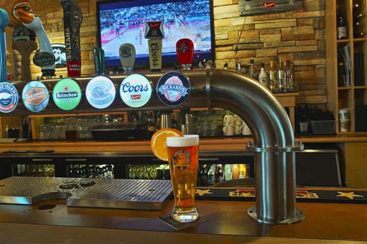 Beer glass on bar counter in front of beer taps