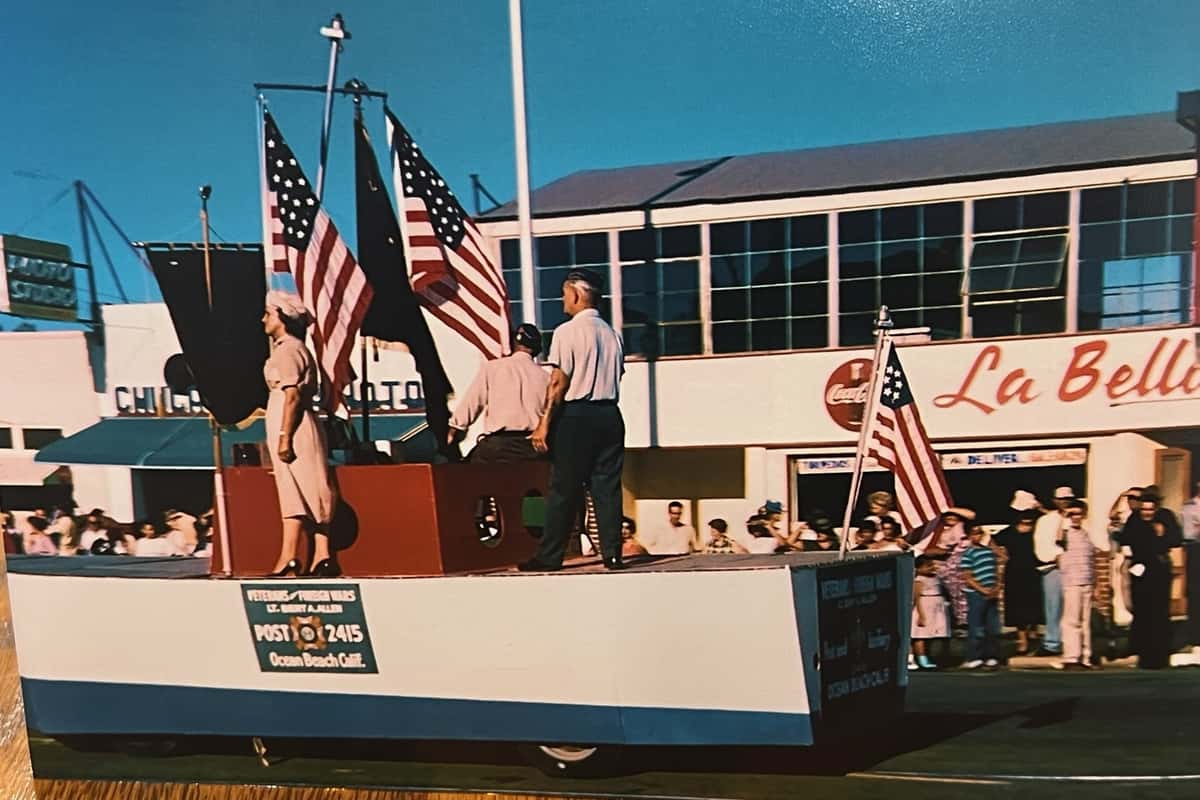 1959 4th of July Parade with Float many Flags la Bella, coca cola logo in the Background with many people