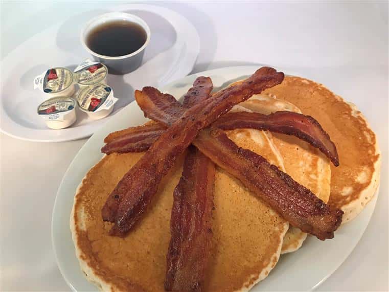 pancakes with bacon on top and syrup and butter on the side