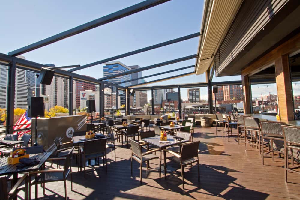 Spacious rooftop dining terrace with open-air seating, skyline views, and contemporary outdoor tables for drinks and dining.