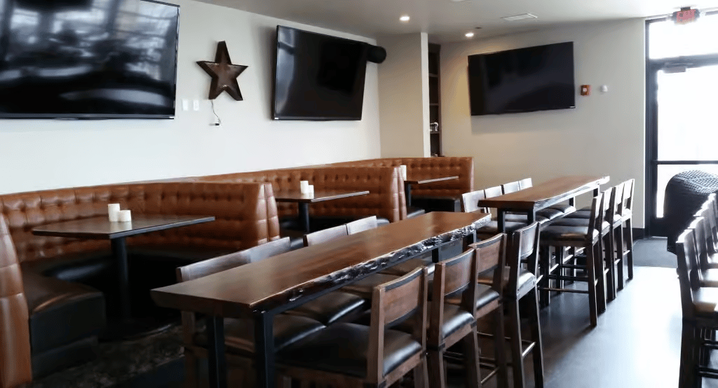 Semi-private dining area with high-top tables, leather banquettes, and televisions for group dining, watch parties, and casual events.