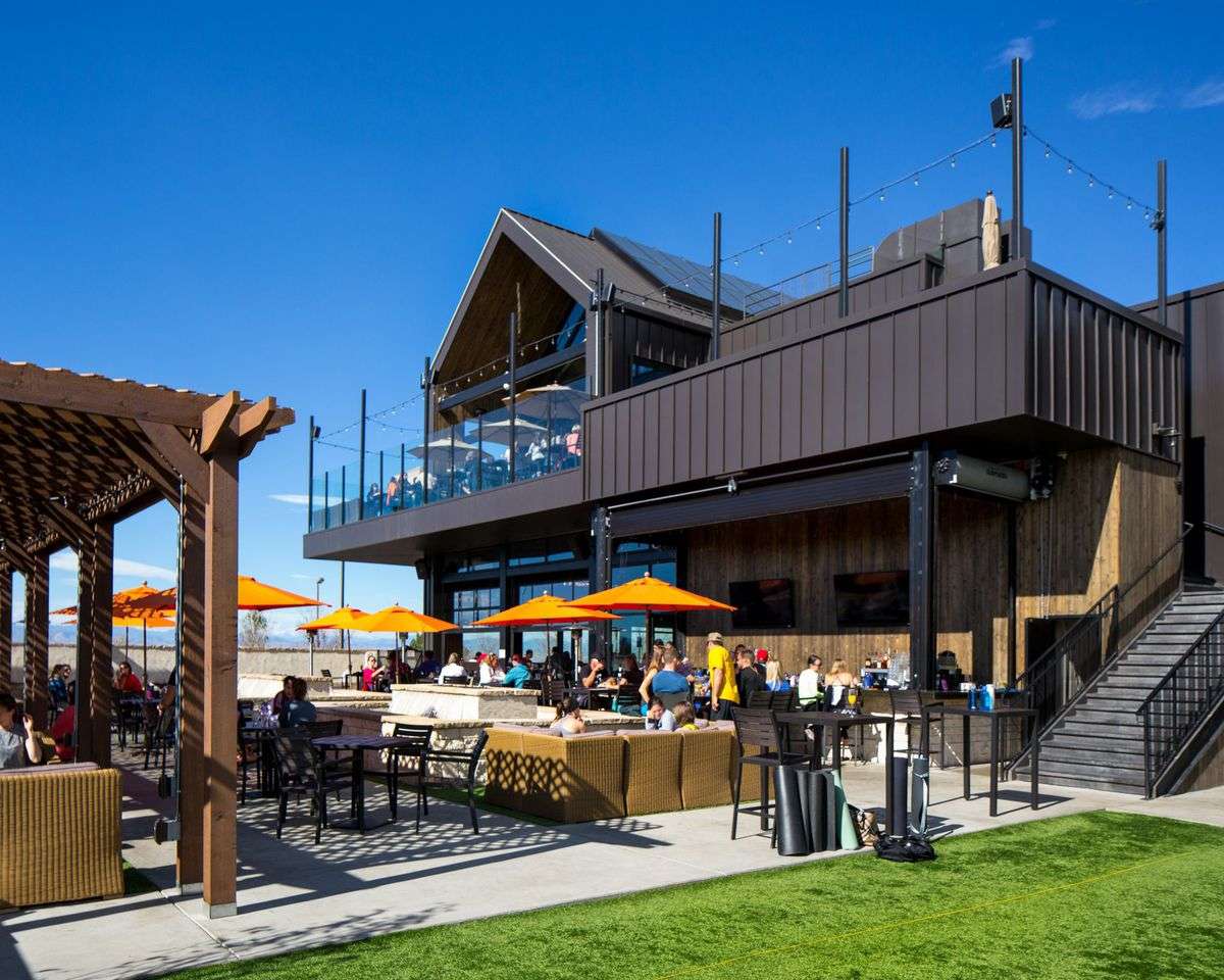 Modern ViewHouse restaurant and rooftop patio with outdoor seating, lounge areas, orange umbrellas, and a vibrant atmosphere for dining and social gatherings.