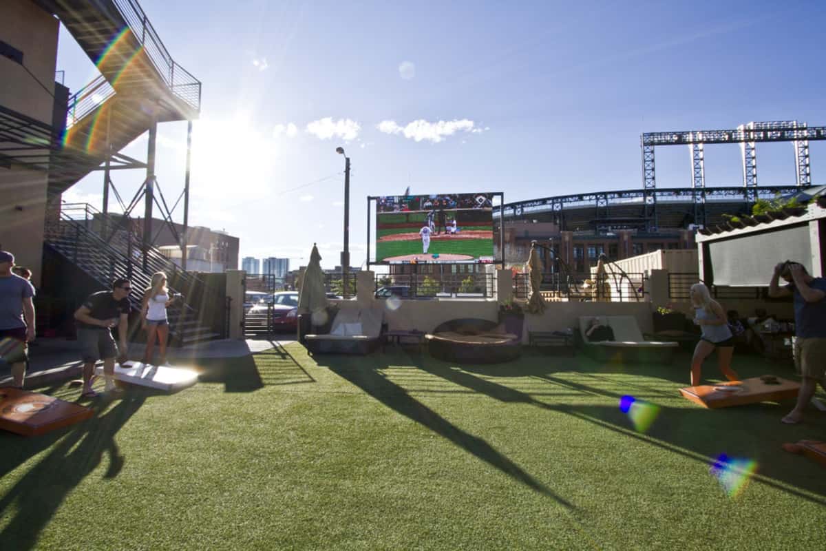 Rooftop lawn and outdoor entertainment space with giant video screen, yard games, and city views for social events and game-day gatherings.