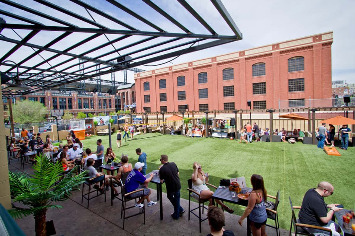 Expansive rooftop beer garden and lawn area with outdoor seating, social games, and city views for group events and casual dining.