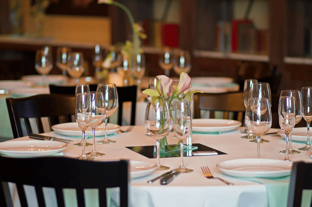 Formally set dining tables with wine glasses, floral centerpieces, and elegant place settings for private events and special occasions.