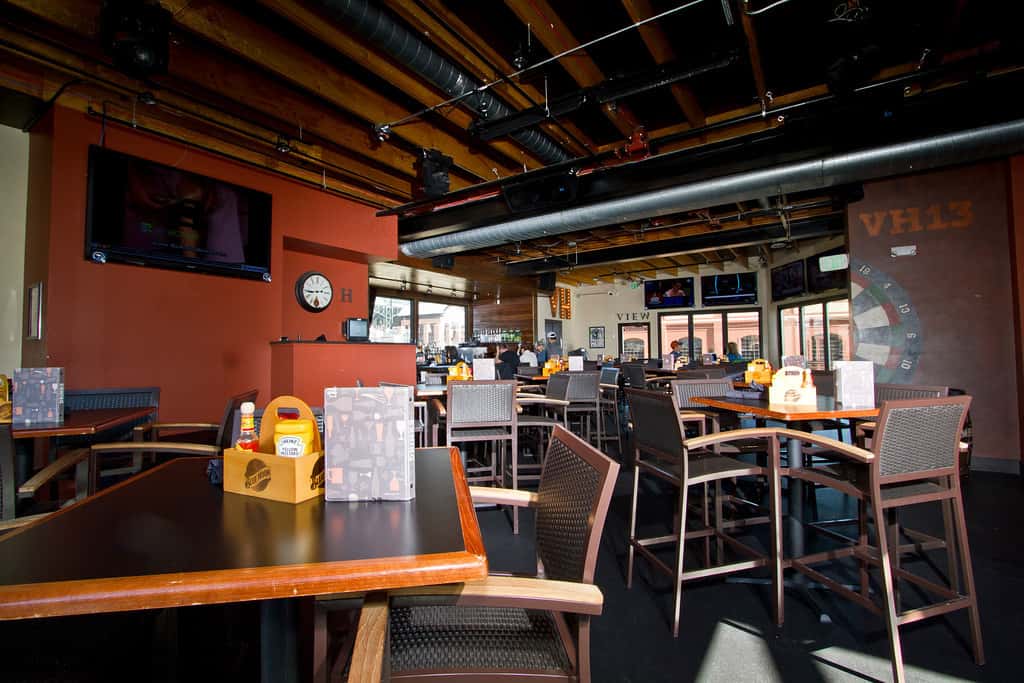Modern restaurant dining room with high-top tables, televisions, and casual seating designed for sports viewing and group dining.