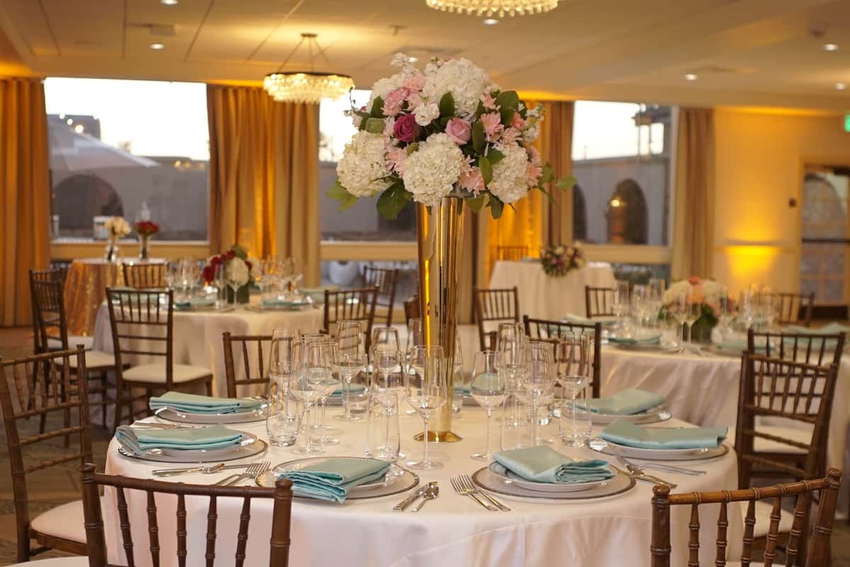Elegant wedding reception ballroom with floral centerpieces, formal table settings, and warm ambient lighting for upscale celebrations