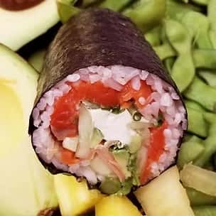 Sliced sushi burrito roll filled with salmon, avocado, cucumber, and cream cheese, wrapped in nori with sticky rice – a fusion of Japanese sushi and handheld burrito style.