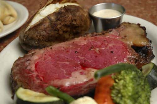 prime rib with vegetables and a baked potato
