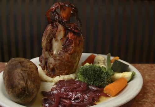 meat on the bone with mashed potatoes, baked potato, and vegetables