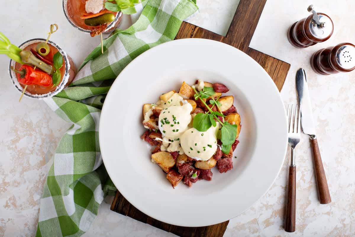 breakfast eggs benedicts over potatoes and bloody mary's