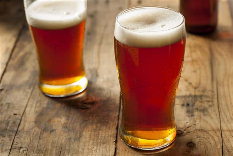 Two full beer glasses on rustic wood table