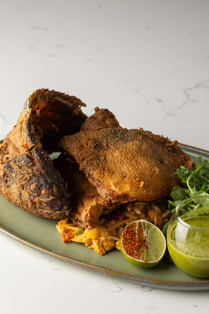 crispy whole snapper on a plate with a lime