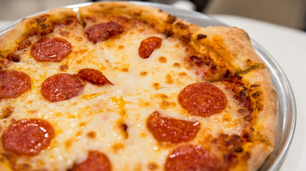Close-up of a pepperoni pizza slice with bubbly melted cheese and visible crust.
