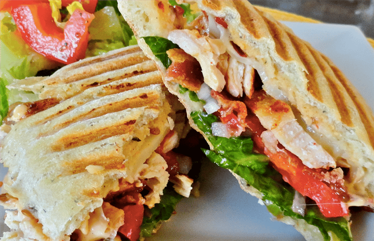 chicken panini topped with tomatoes, lettice and cheese