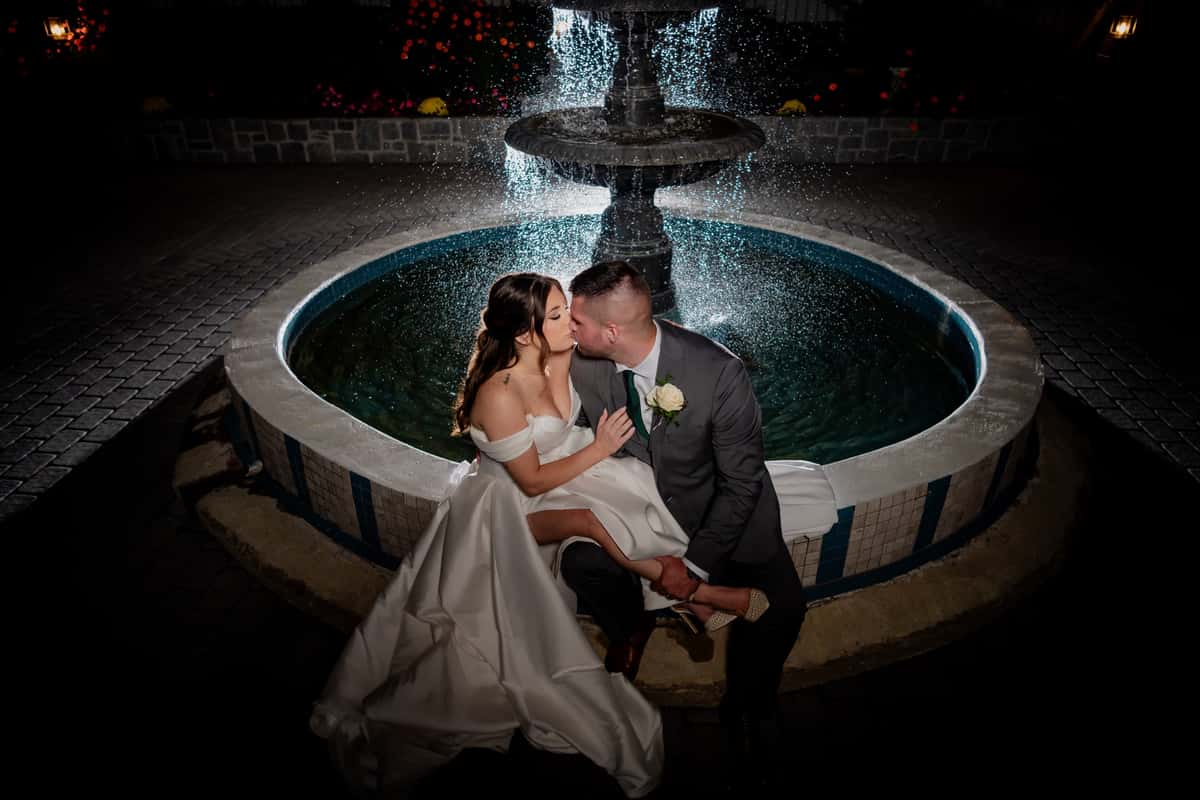a woman and man kissing in front of a fountain