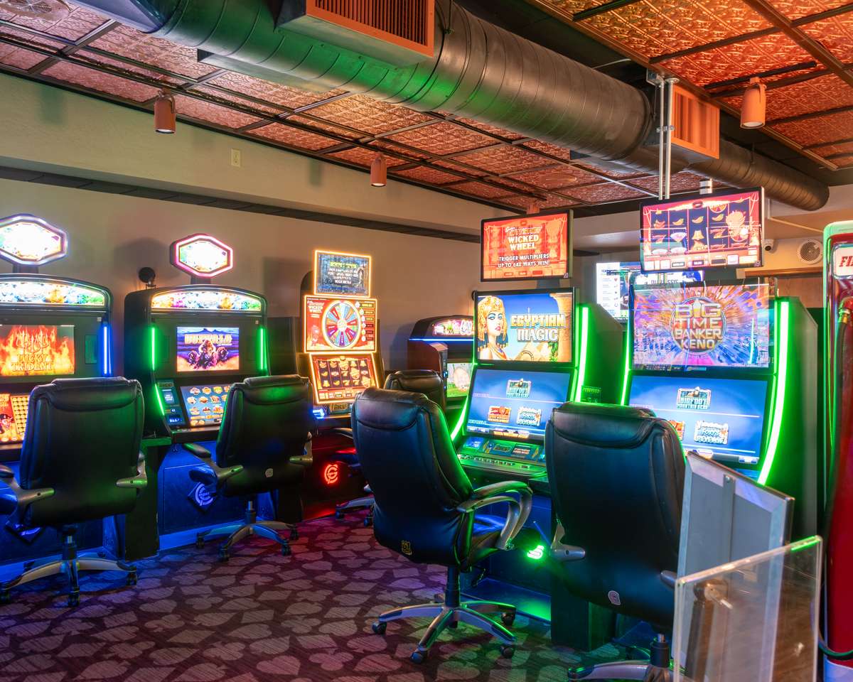 Bright gaming area featuring slot machines, comfortable seating, and colorful lighting inside Montana Jack's Casino.