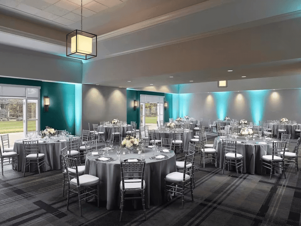 Modern banquet hall with round dining tables, soft blue lighting, and sophisticated event venue atmosphere