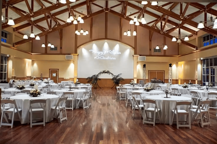Rustic modern wedding venue with vaulted wooden ceilings, dance floor, and elegant reception seating