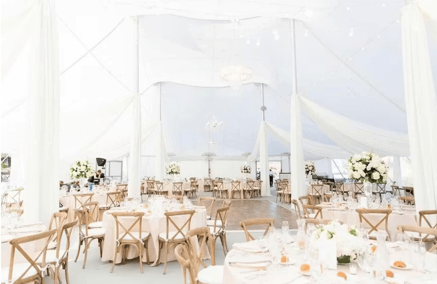 Bright white tented wedding reception with elegant dining tables and airy upscale event styling