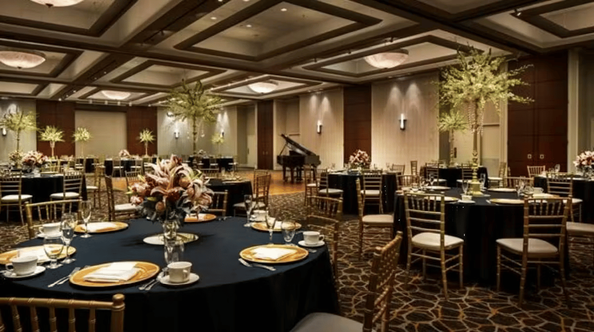 Elegant private dining room with grand piano, formal table settings, and upscale banquet atmosphere