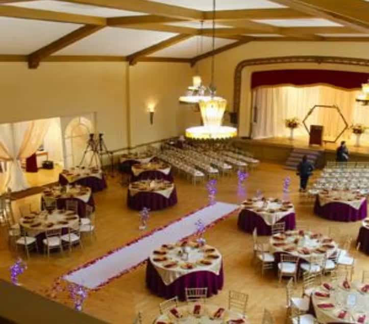 Grand ballroom event space with elevated stage, chandeliers, and sophisticated banquet seating arrangement