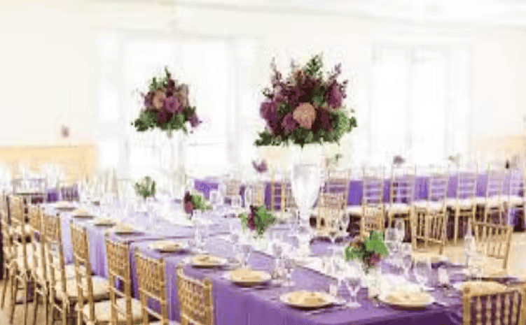 Luxury wedding reception table settings with floral centerpieces, gold chairs, and elegant ballroom decor