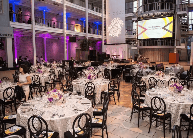 Modern wedding reception venue with floral centerpieces, elegant table settings, and romantic ballroom lighting