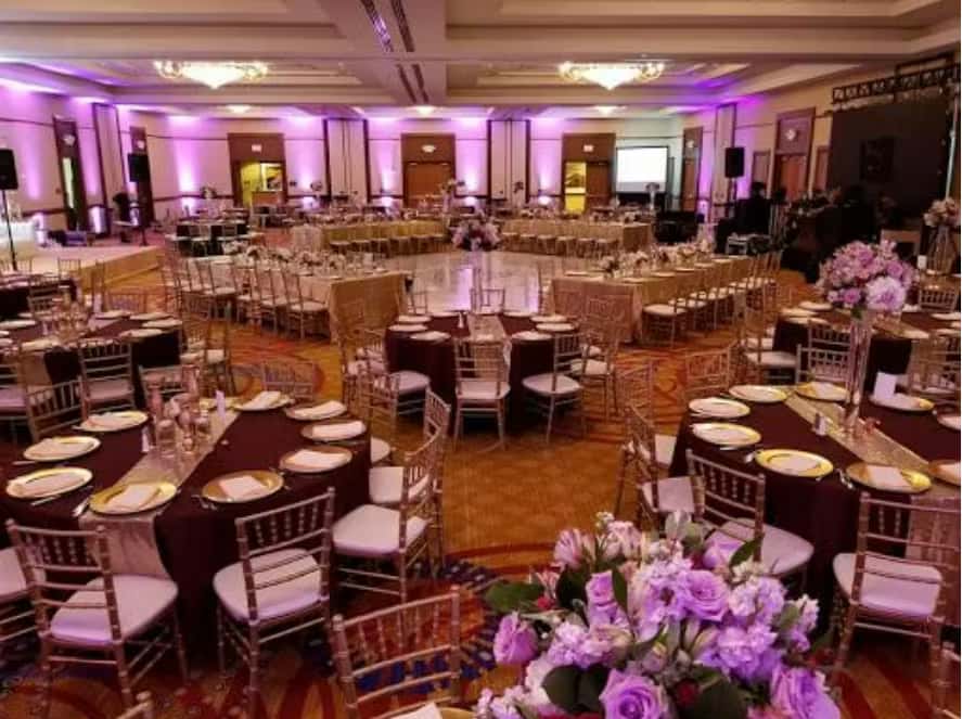 Upscale ballroom reception with purple ambient lighting, floral centerpieces, and elegant banquet seating