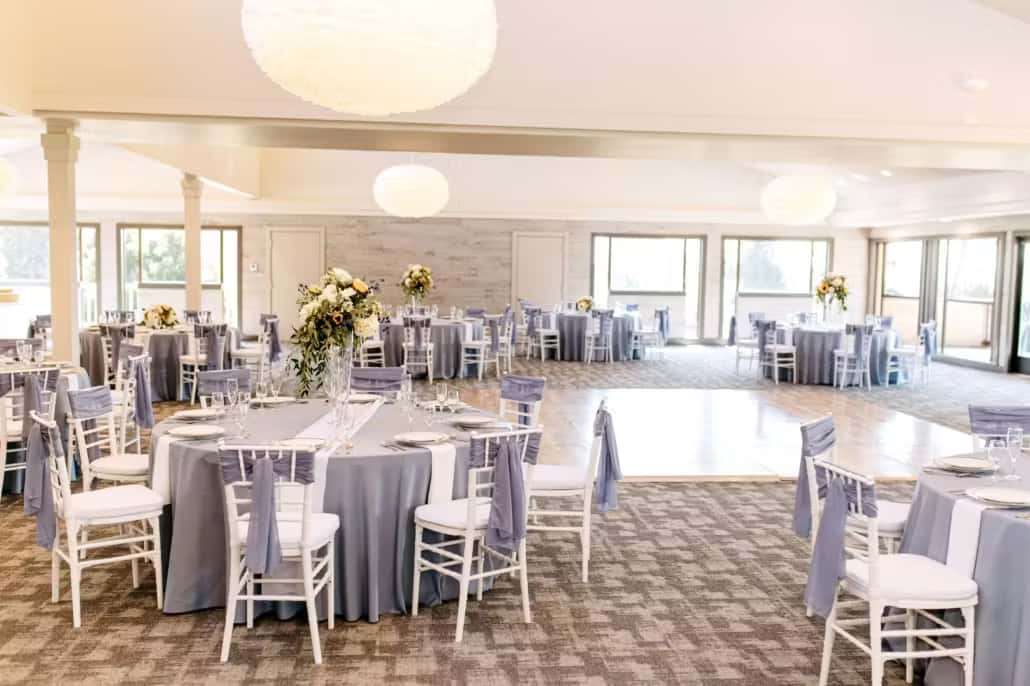 Modern coastal banquet hall with round dining tables, soft natural lighting, and elegant event ambiance